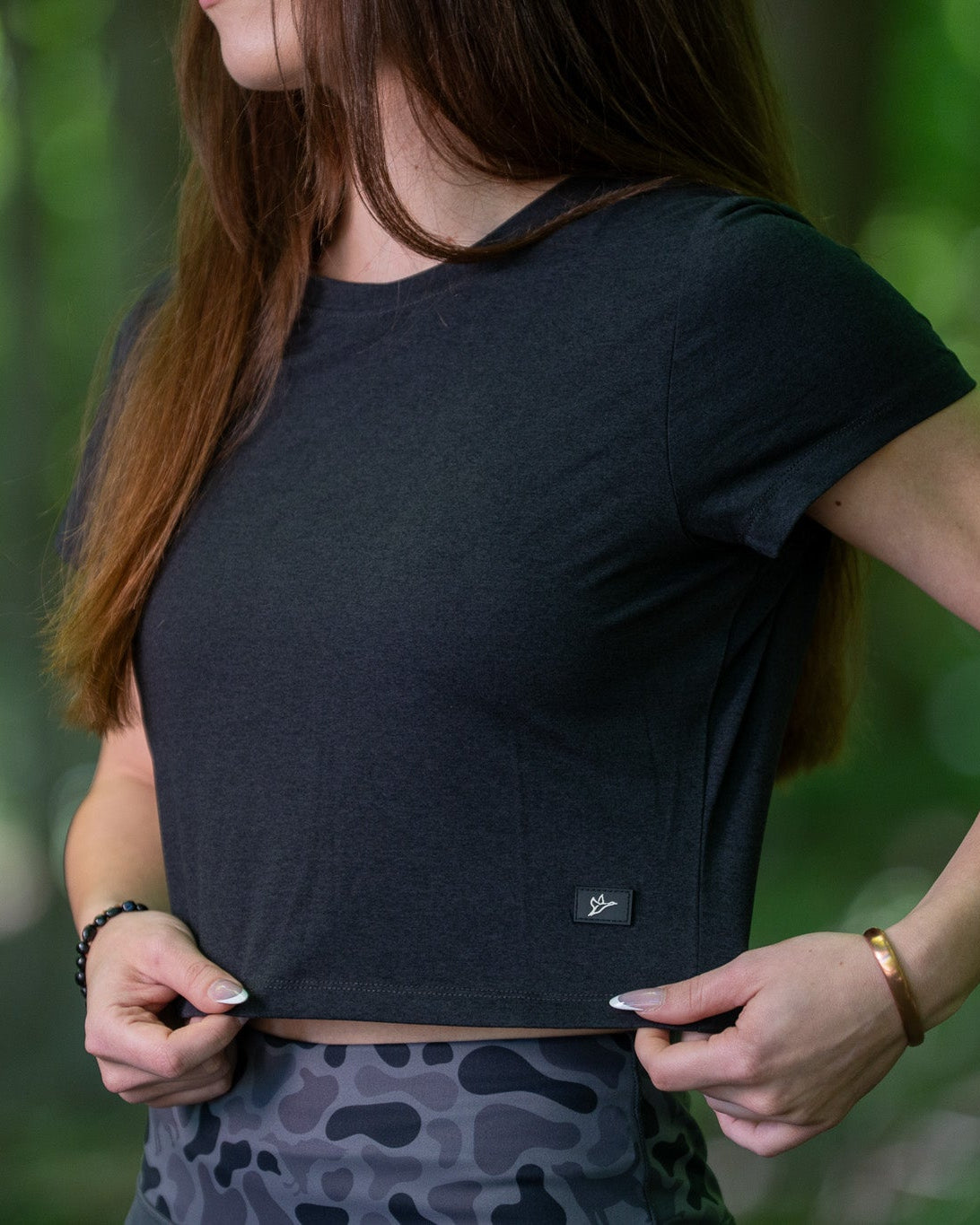 Person wearing a black crop top with a blurred green background