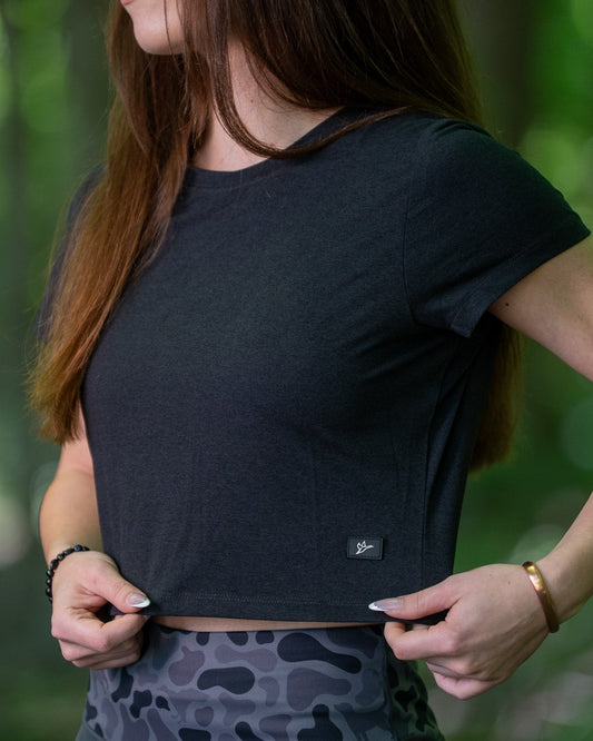 Person wearing a black crop top with a blurred green background