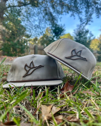 Two Goat Rope™ Boudin embroidered rope hats with a combat icon, lying in green grass.